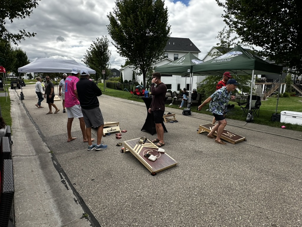 Players and spectators gathered around multiple cornhole courts
