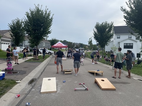 Cornhole courts and neighbors filling the neighborhood street